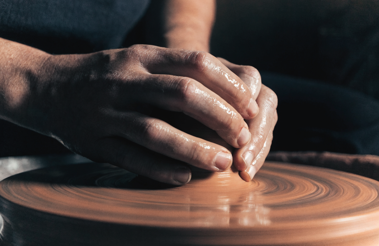 Les mains de la potière au tour, en train de creuser la paroi d'un bol